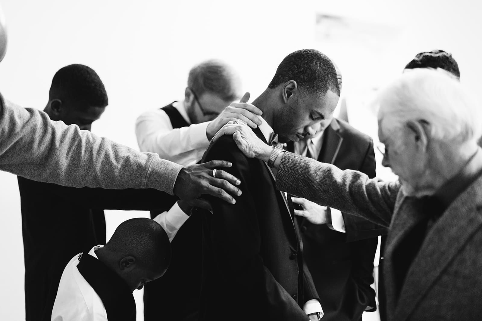 Friends and family surround Tyler for a prayer befor his First Look