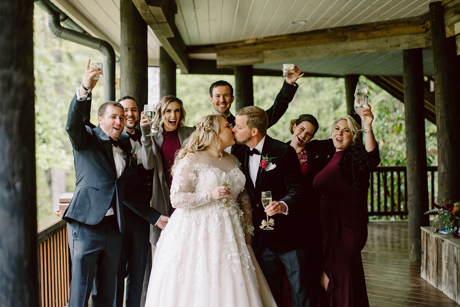 Holly and Will kiss while their bridal party cheers during their Asheville Wedding Day as photographed by Wilder Weddings Collective