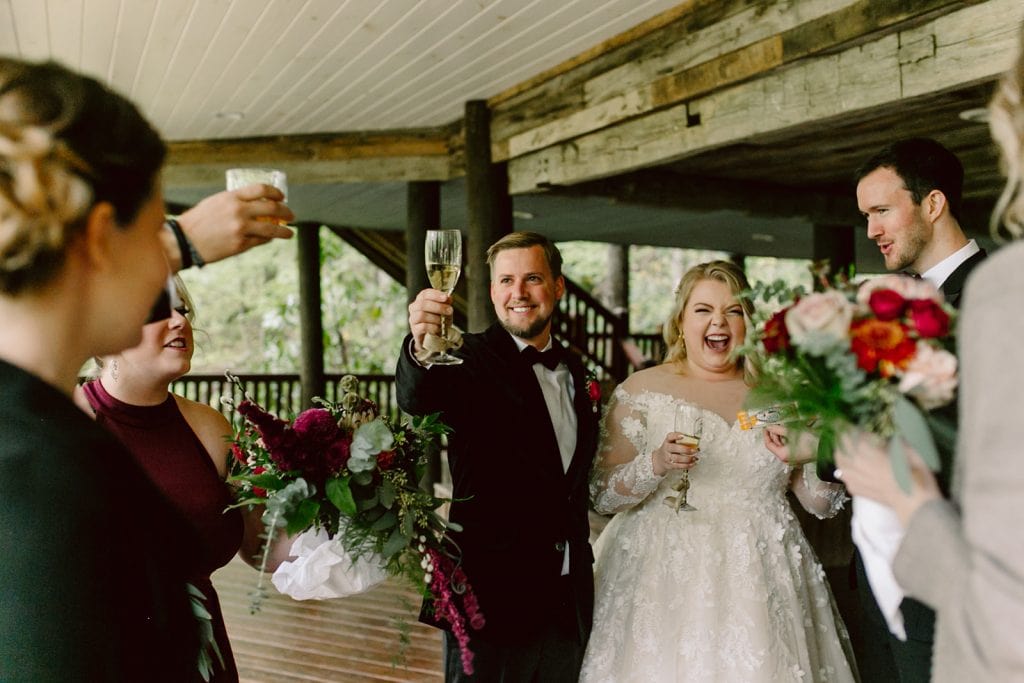A happy couple and their friends toast champagne during their Asheville Wedding celebration