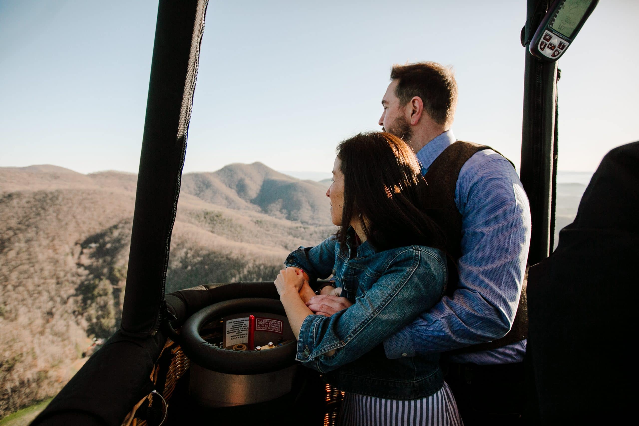 Mindy and Shane embrace as they fly over the Blue Ridge Mountains in a hot air balloon on their Asheville Adventure Elopement