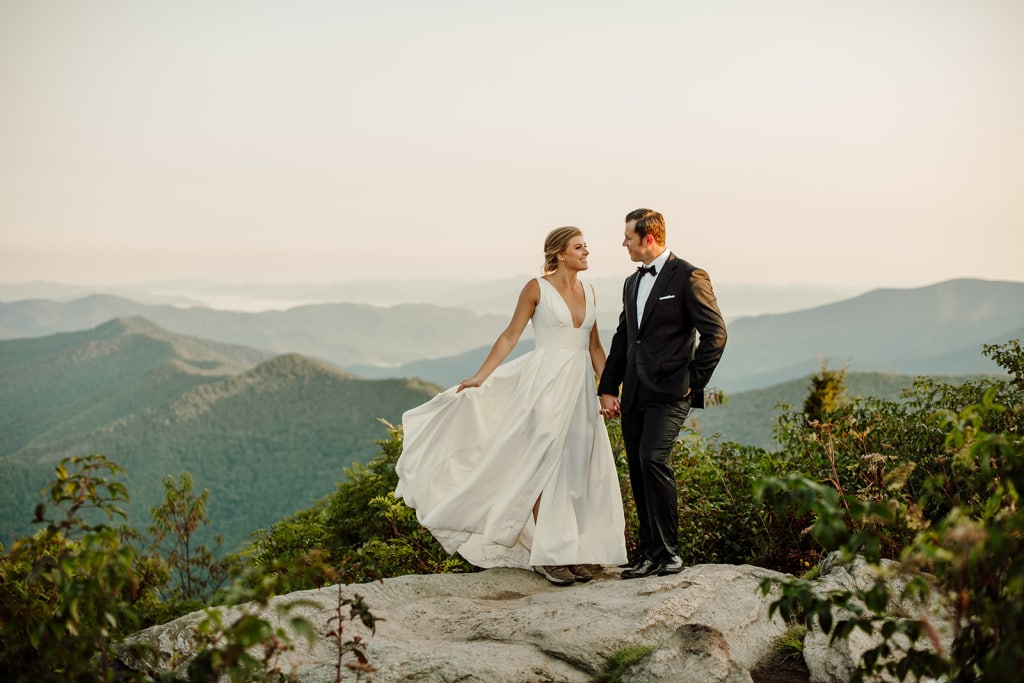 Madison + Kyle join hands on a mountaintop during their intimate Asheville Adventure Wedding