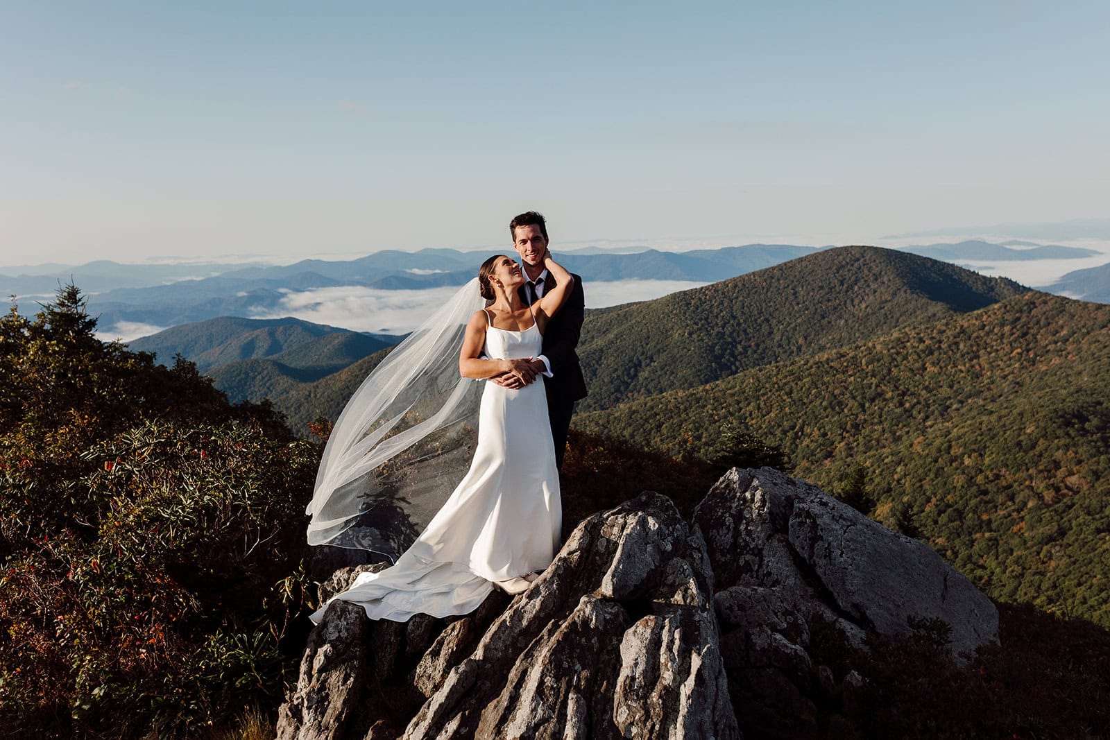 bailey+daniel stand on a mountaintop during their adventure elopement in the Blue Ridge Mountains